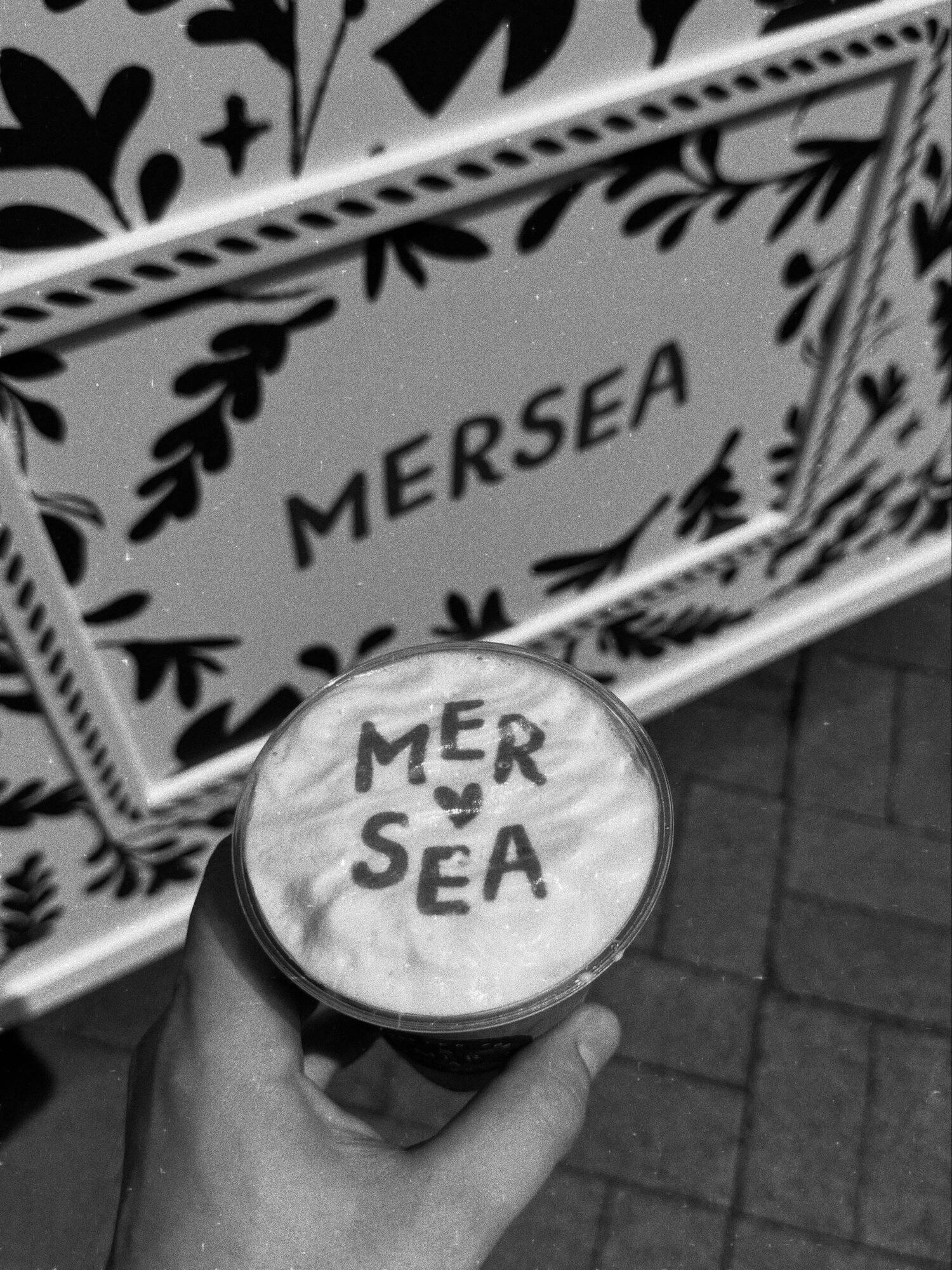 Mersea logo latte held in front of the custom branded coffee cart